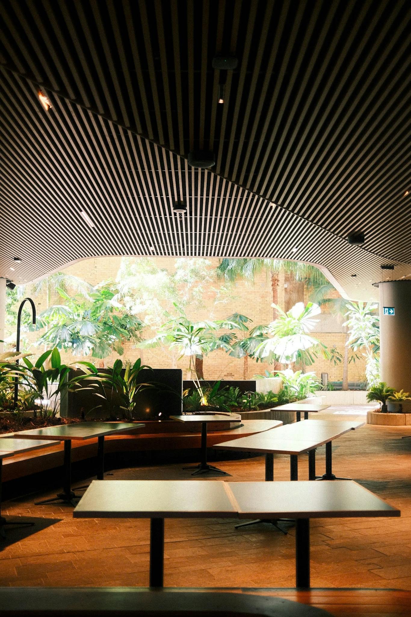 A stylish indoor space with greenery, wooden tables, and seating arrangements.