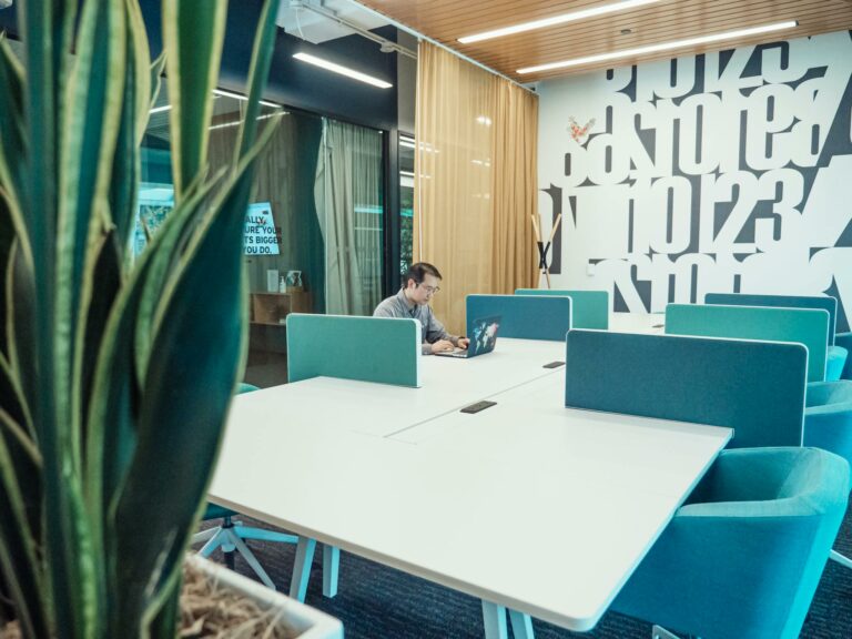 An Asian man works on his laptop in a stylish and modern office with creative decor.